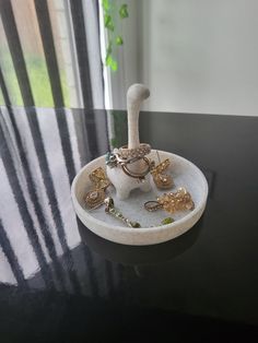 a black table topped with a white bowl filled with rings and other items on top of it