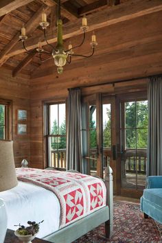 a bed sitting in a bedroom under a chandelier next to a window with sliding glass doors