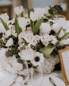 a bouquet of white flowers sitting on top of a table next to a framed photo