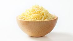 shredded cheese in a wooden bowl on a white background