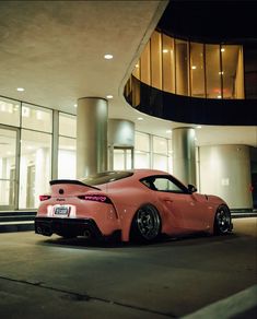 a pink sports car parked in front of a building