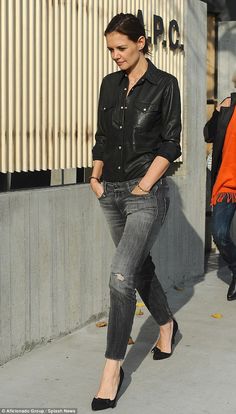 a woman in black shirt and jeans walking on sidewalk