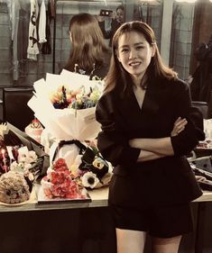 a woman standing in front of a table with cakes on it