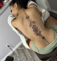 a woman with a tattoo on her back is sitting at a desk and looking down