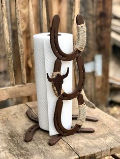 two white and brown paper towels are sitting on a wooden chair with a cow head hanging from it's side