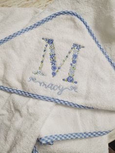 two towels with embroidered letters on them are laying next to each other and one has the letter m on it