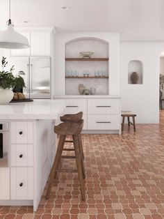 a kitchen with white cabinets and an orange floor tiles pattern on the floor, along with two stools