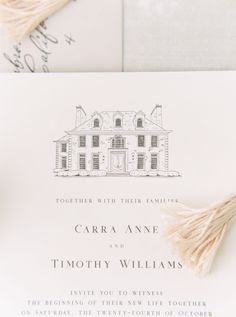 the wedding stationery is laid out on top of an envelope with tassels