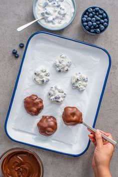 someone is decorating blueberries and cream on a tray