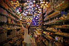 a woman is standing in the middle of a store filled with lights and souvenirs