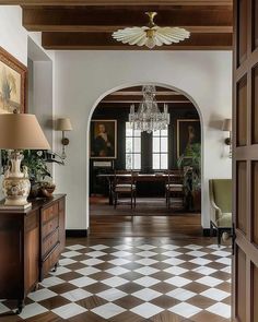 an entry way with a chandelier and checkered flooring in the hallway