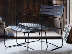 a metal chair sitting on top of a white rug next to a book shelf filled with books