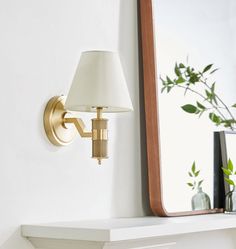 a white mantle with a lamp and mirror on it