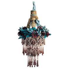 a chandelier hanging from the ceiling with flowers and leaves on it's sides