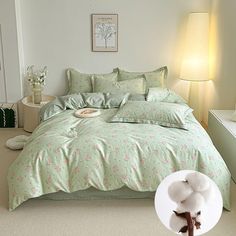 a bedroom with a bed covered in green comforters and pink flowers on the covers