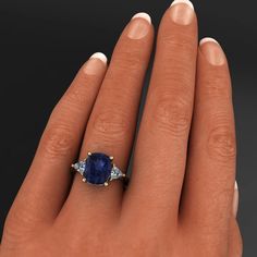 a woman's hand with an oval shaped blue sapphire and diamond ring on it