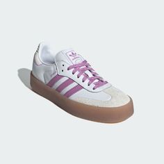 a white and pink adidas sneakers with gum soles on the bottom, in front of a white background