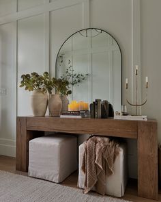 a wooden table topped with a mirror and two vases filled with flowers on top of it