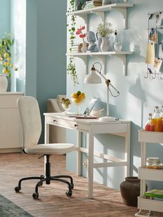 a white desk and chair in a room with shelves on the wall behind it,