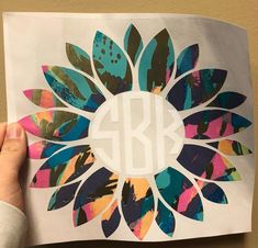 a person holding up a piece of paper with the letter b on it and an image of a flower