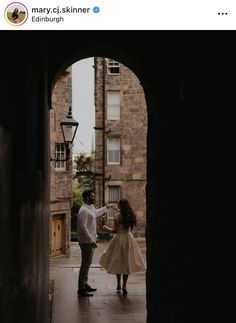 a man and woman dancing in an archway