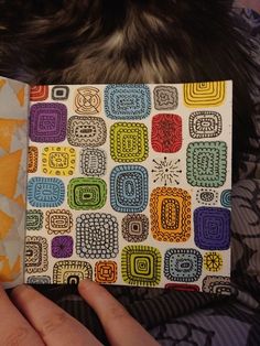 a person holding a book with colorful designs on it