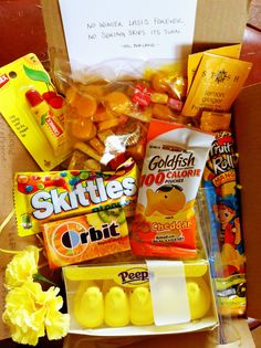 a box filled with snacks and candy sitting on top of a table next to a note