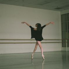 a ballerina in a black dress is posing for the camera with her arms outstretched