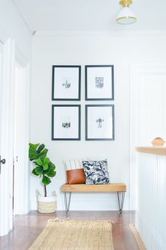 a room with pictures on the wall and a bench in front of it, along with a rug