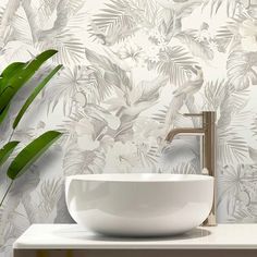 a white bowl sink sitting on top of a counter next to a green leafy wallpaper