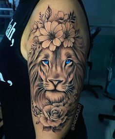 a woman's arm with a lion and flowers tattoo on her left shoulder, which has blue eyes