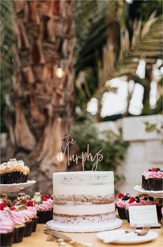 there is a cake on the table with cupcakes and other desserts around it