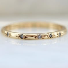 a yellow gold band with three diamonds on the inside and outside, sitting on a white surface