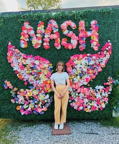 a woman standing in front of a flower wall