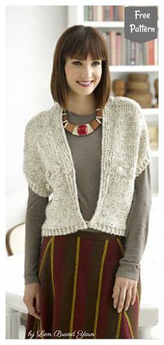 a woman standing in front of a bookshelf wearing a cardigan and skirt