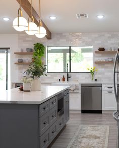 a modern kitchen with stainless steel appliances and white counter tops, along with open shelving