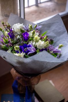 a bouquet of flowers sitting on top of a wooden table next to a glass window