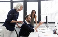 two women and a man in an office setting looking at something on the computer screen