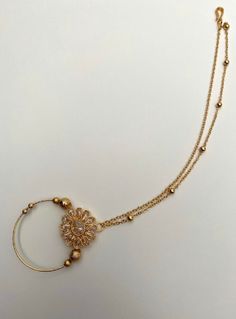 a gold necklace with beads and a flower on the end is hanging from a chain