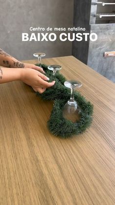 two wine glasses sitting on top of a wooden table next to a person's hand