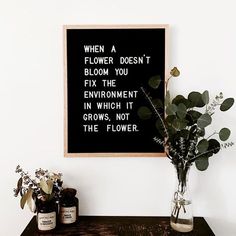 a vase filled with flowers sitting on top of a wooden table next to a blackboard