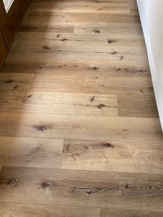 a wooden floor with white walls and wood floors in the corner, next to a window