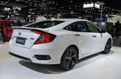 a white honda civic is on display at an auto show