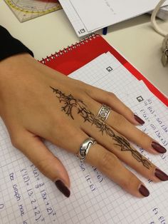 a woman's hand with tattoos on it sitting next to a pen and paper