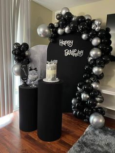 some black and silver balloons are in front of a happy birthday sign on the wall