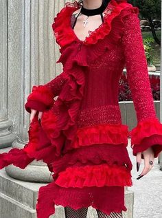 a woman wearing a red dress with ruffles on the bottom and black stockings