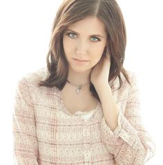 a beautiful young woman posing for a photo with her hand on her chin and looking at the camera