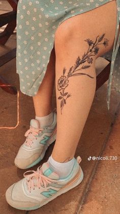 a woman sitting in a chair with her legs crossed and flowers tattooed on the leg