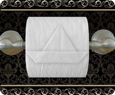 an image of a white paper towel on a black and gold wall mounted tissue dispenser