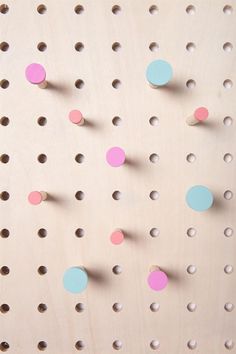 the peg board has several holes in it and is painted pink, blue, and green